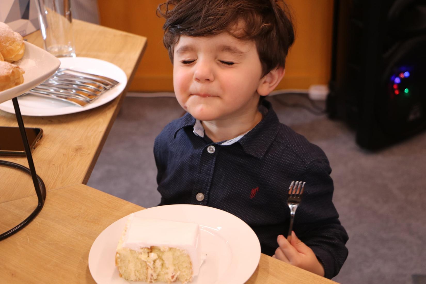 Kid enjoys his slice of cake.