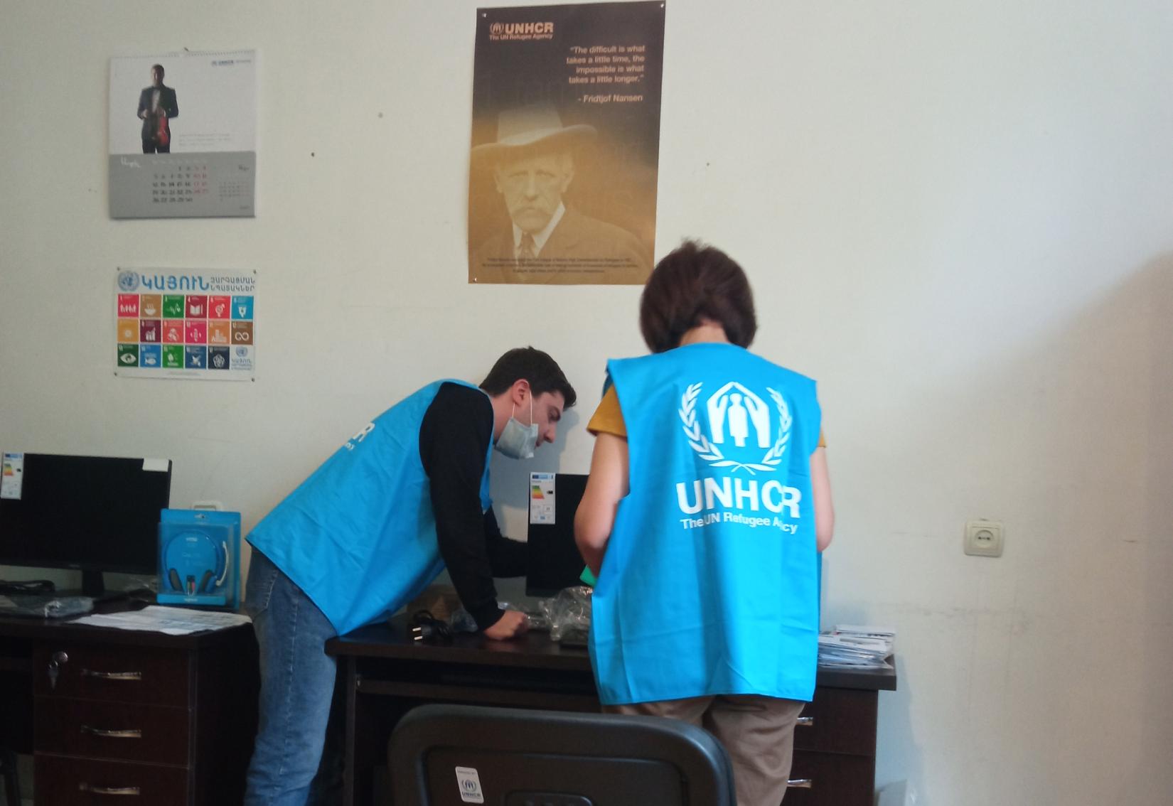 UNHCR staff helps to connect the technical equipment.