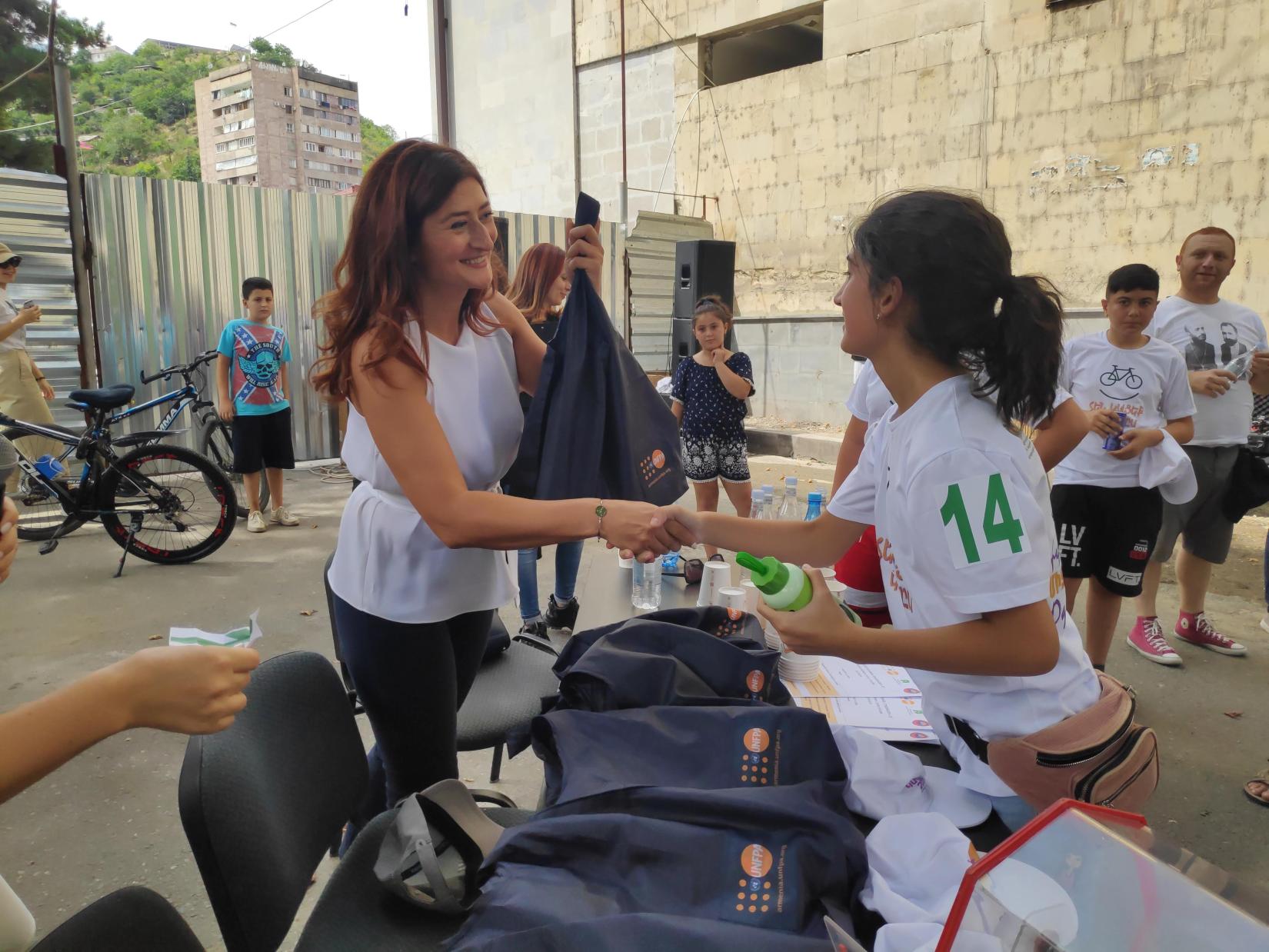 A young participant of the Healthy Bike Run receives a prize from UNFPA Head of Office, Tsovinar Harutyunyan.