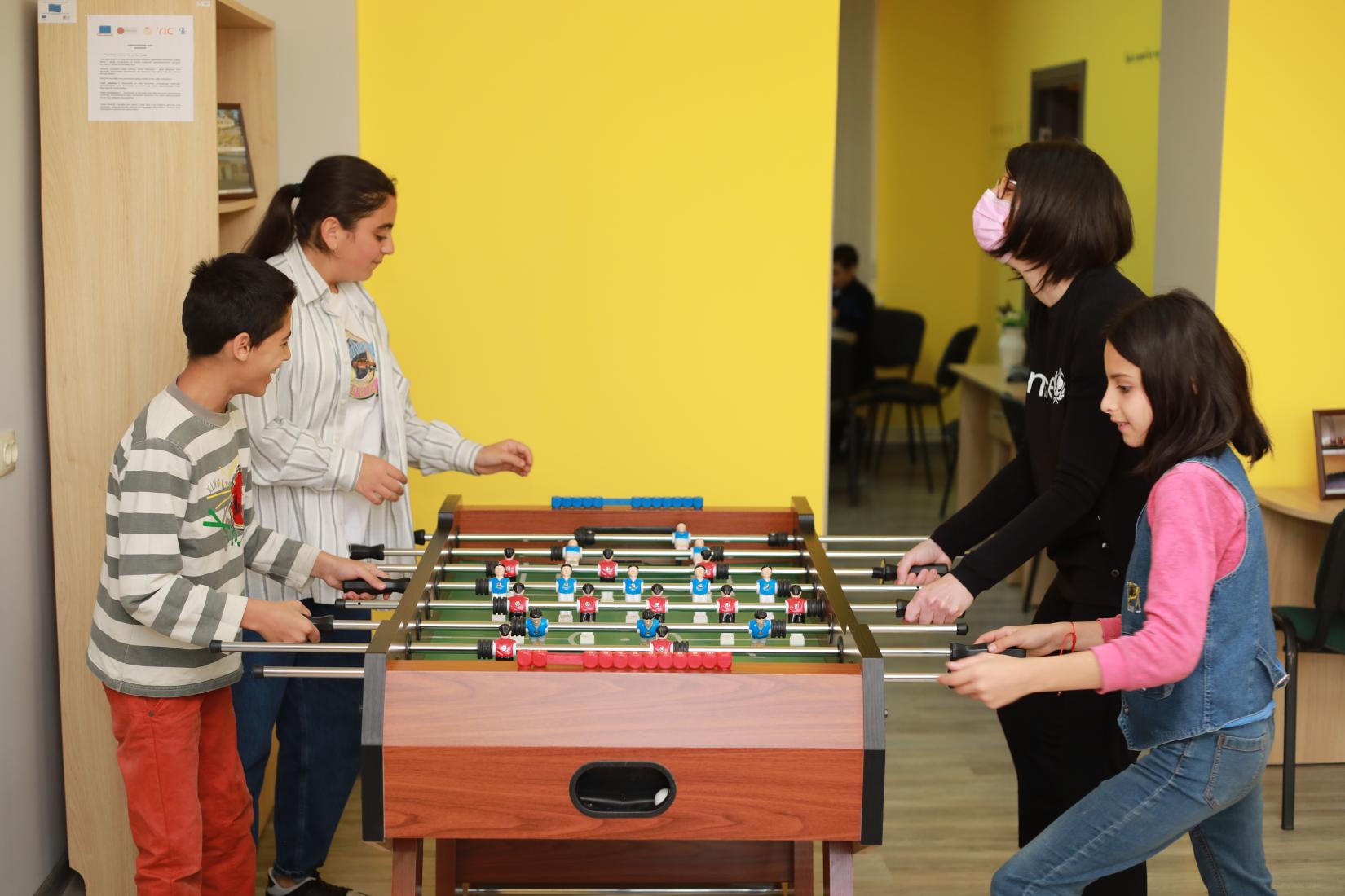 Children play table football with UNICEF staff memeber.