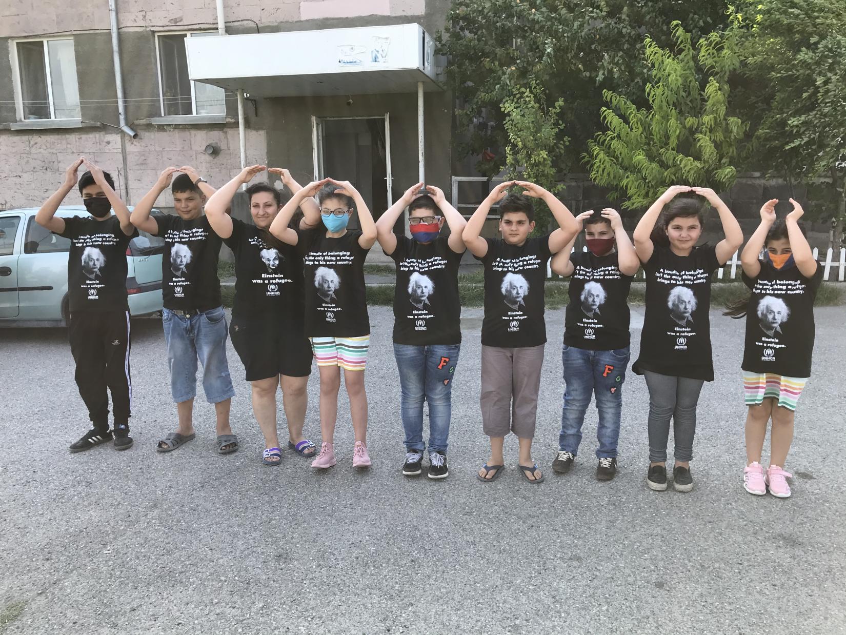 The children showing the symbol of home and UNHCR.