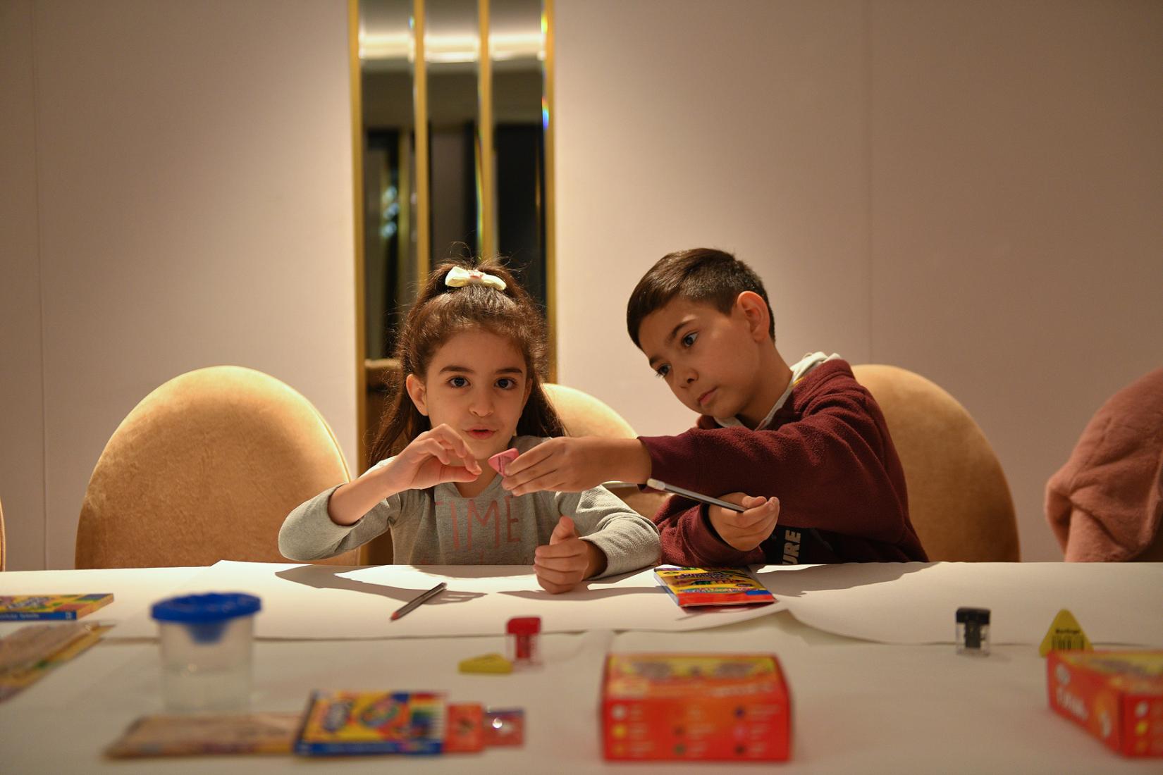 A boy handles an eraser to the girl sitting next to him.