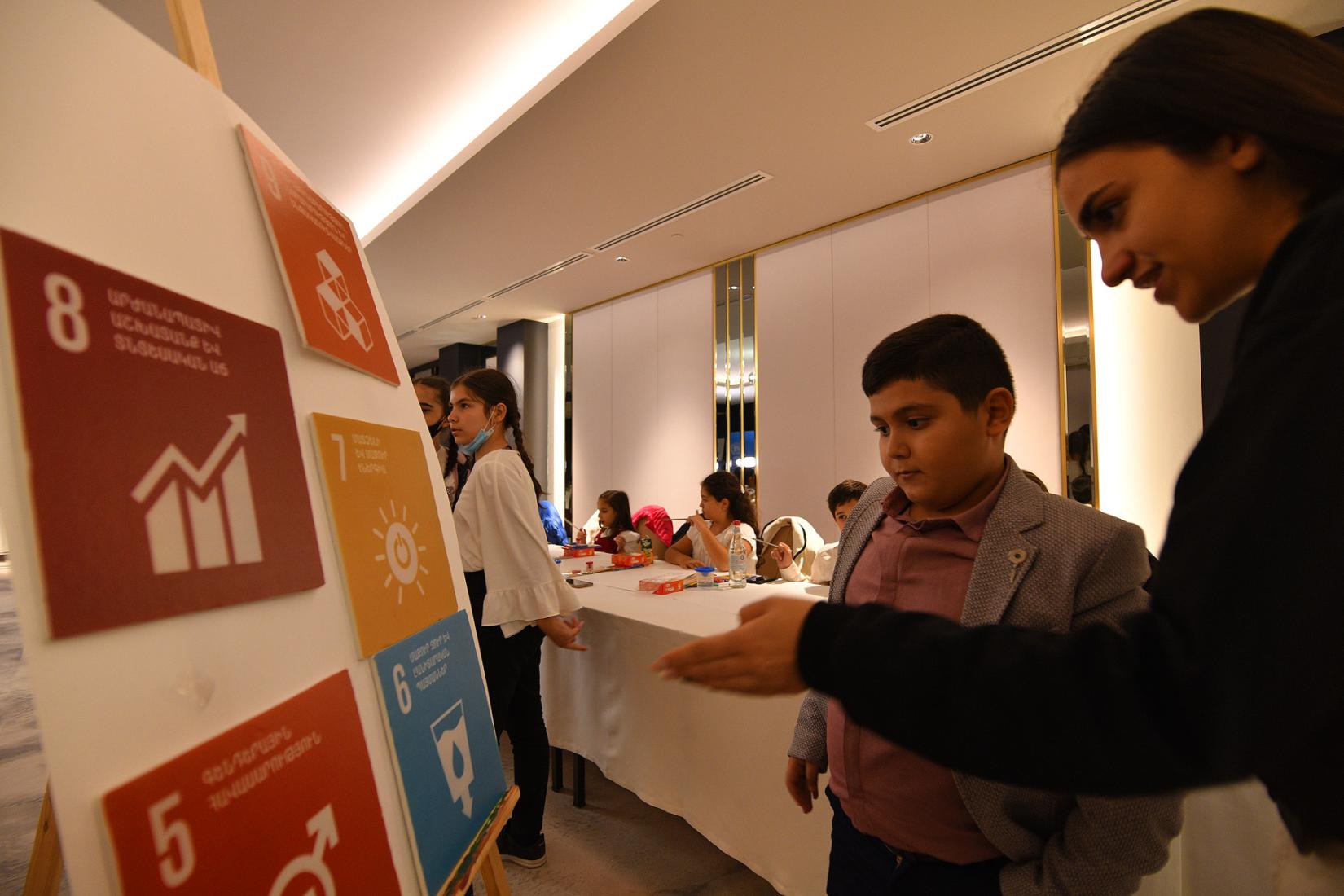 Youth coalition member explains the SDGs to a boy.