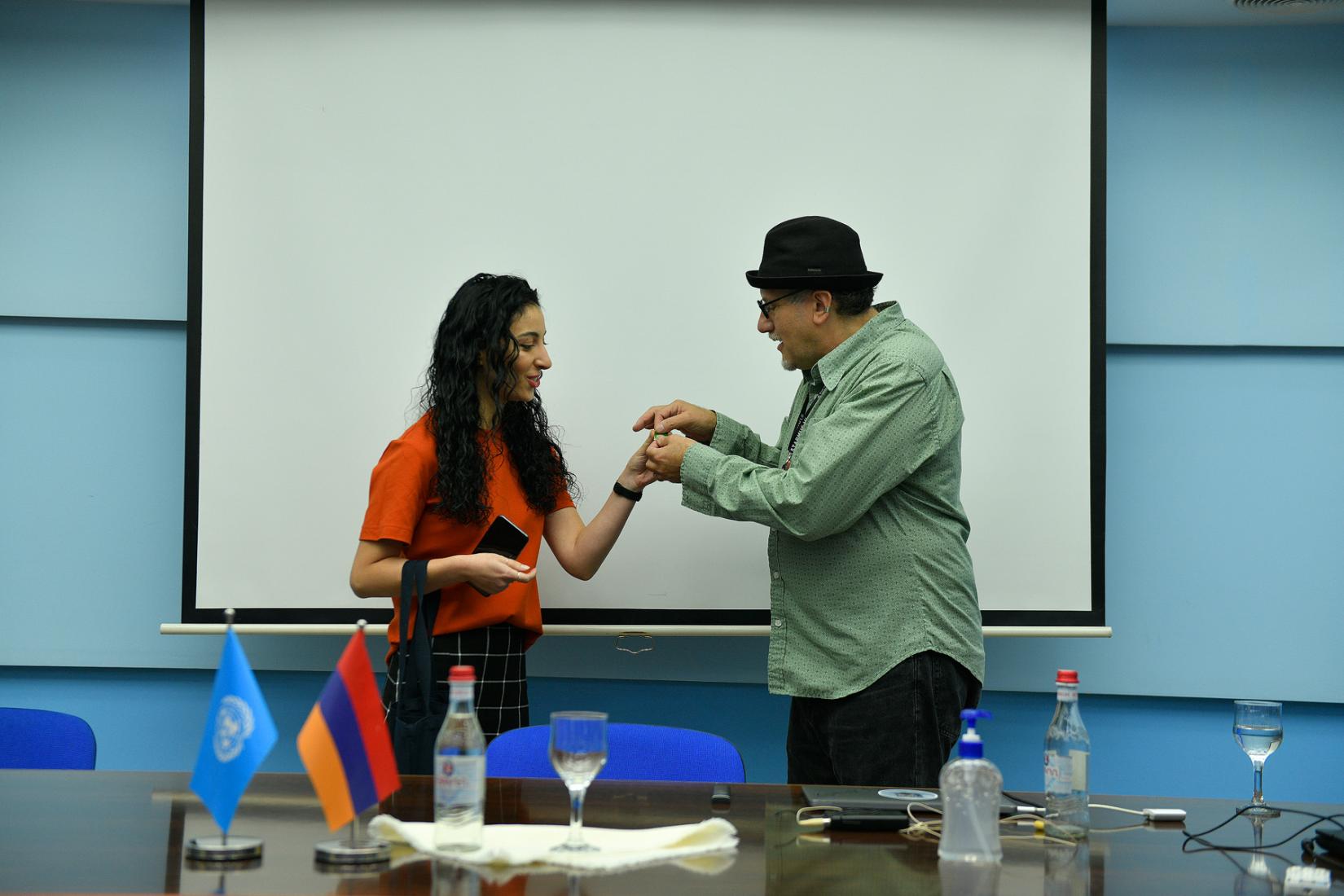 A man receives a symbolic gift from the UN Armenia Natioinal Information Officer Ms. Armine Petrosyan.