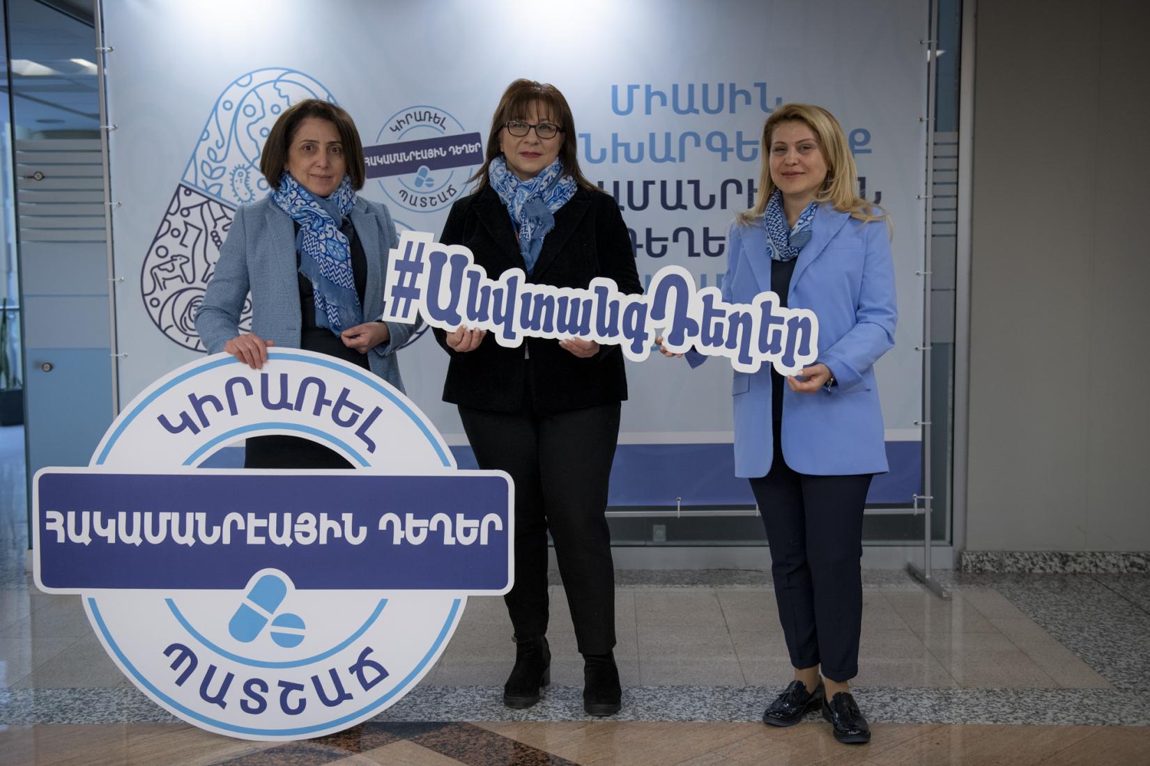Three women holding a banner on the safe use of drugs.