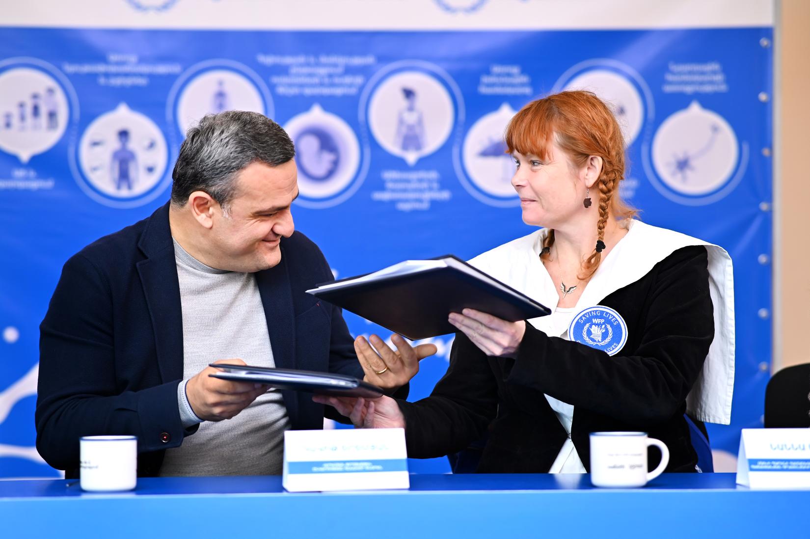 A man and a woman signing cooperation agreement.