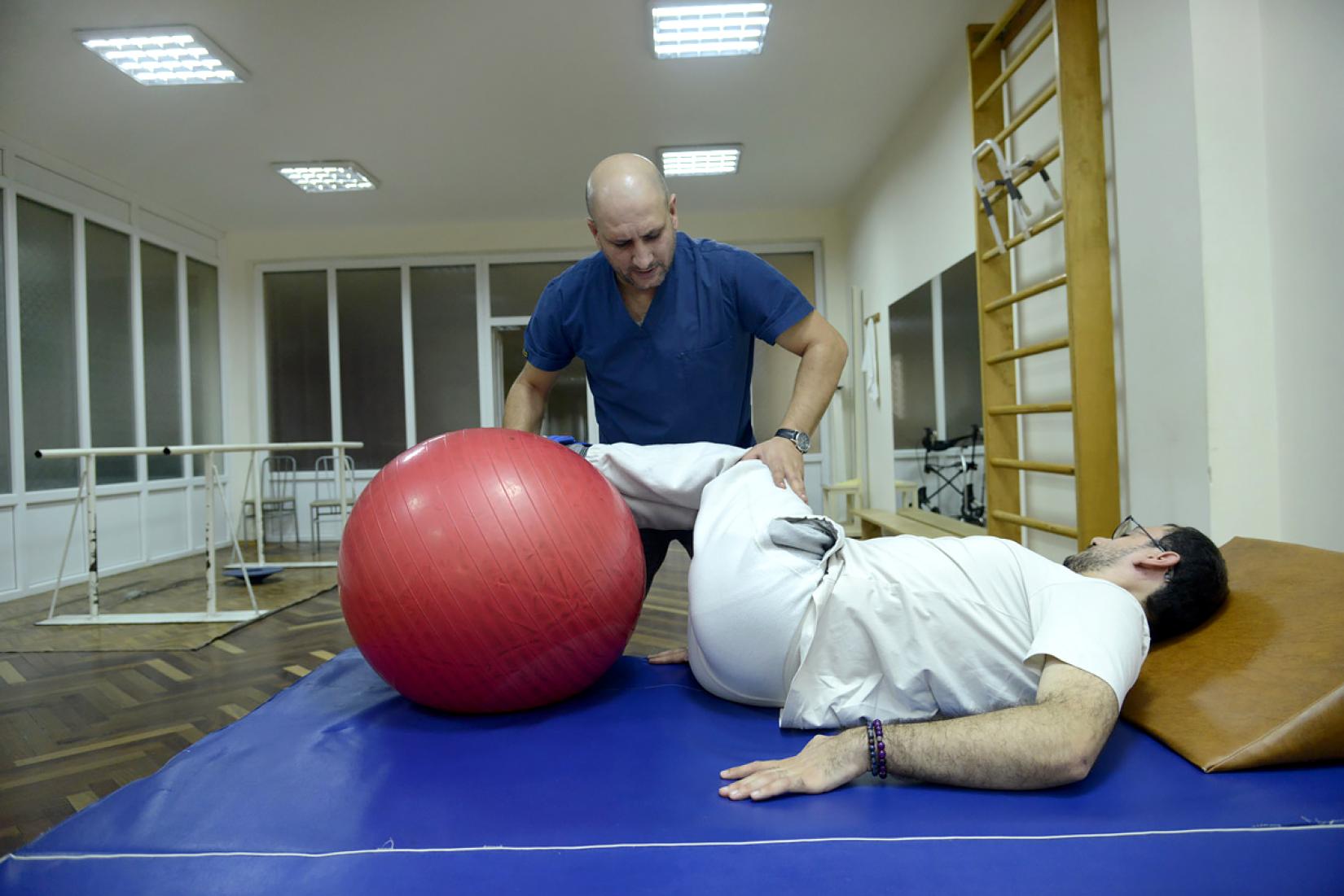 The therapist uses physical therapy techniques for the treatment of a patient after a traumatic brain injury.