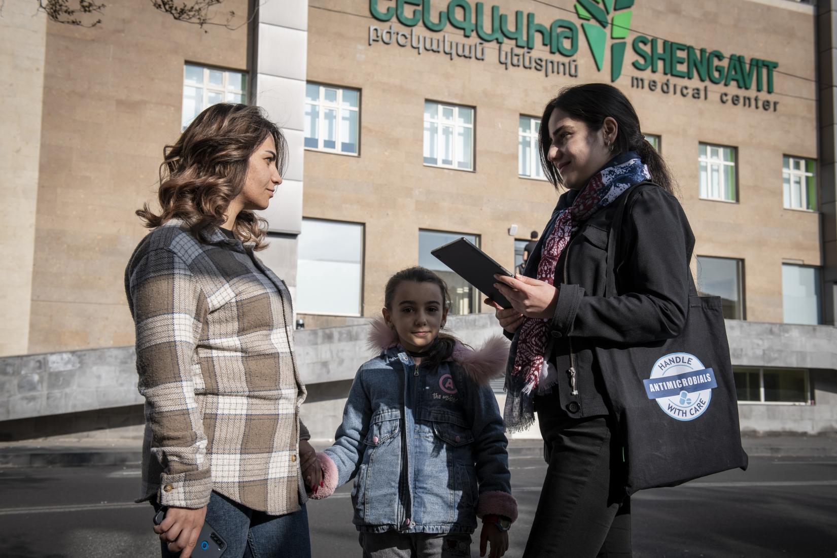 An expert interviewing a woman with a child.