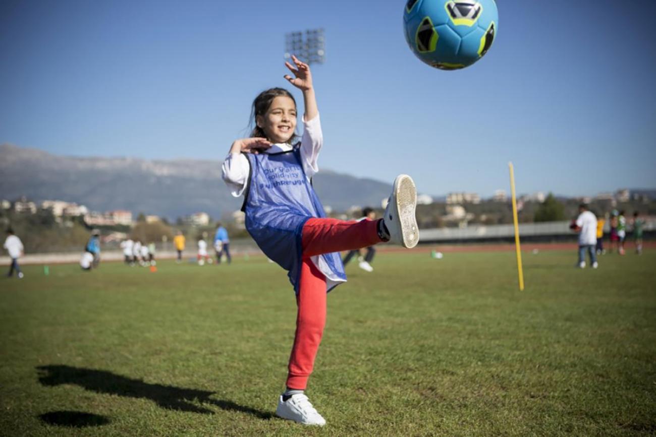 Young girl kicks ball during a refugee solidarity event.