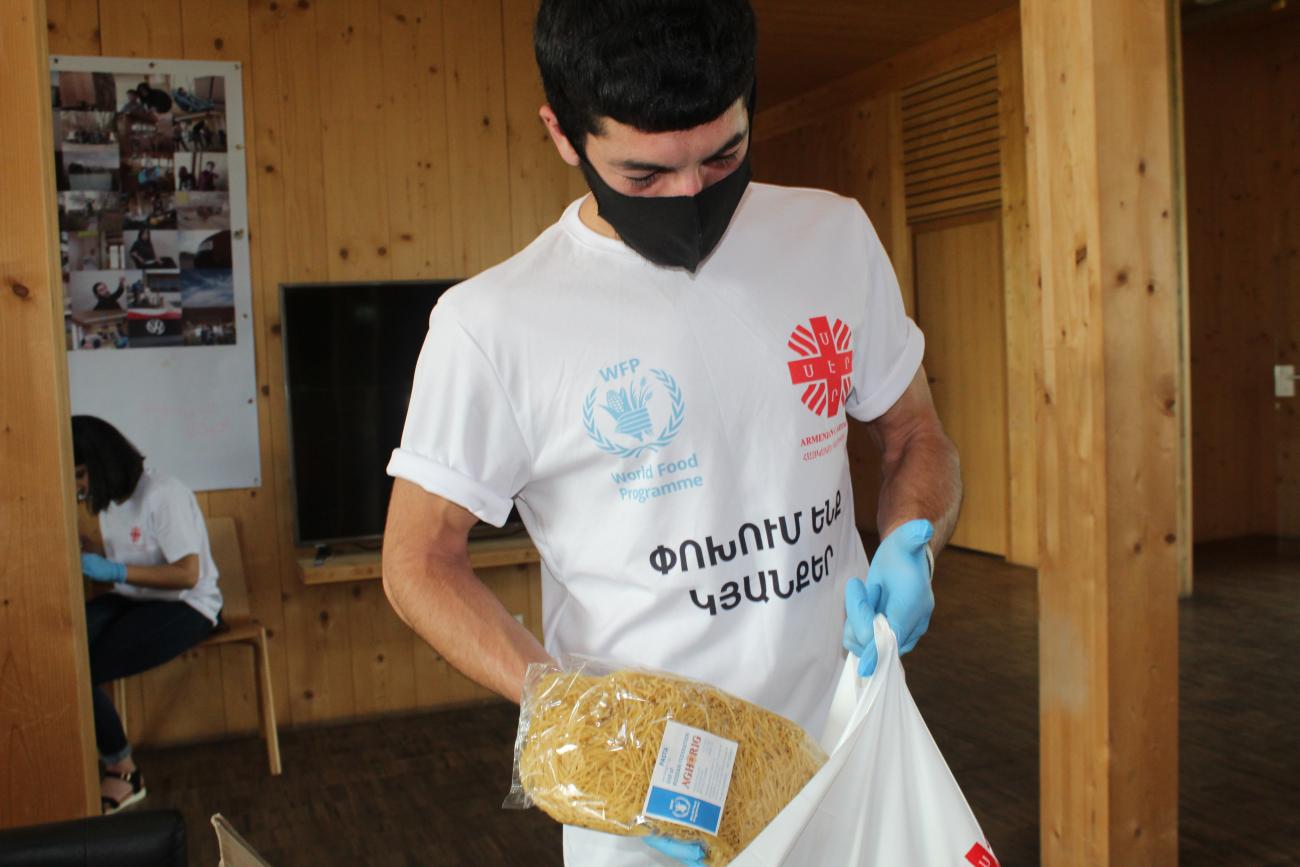 A young man puts WFP branded pasta into a bag.