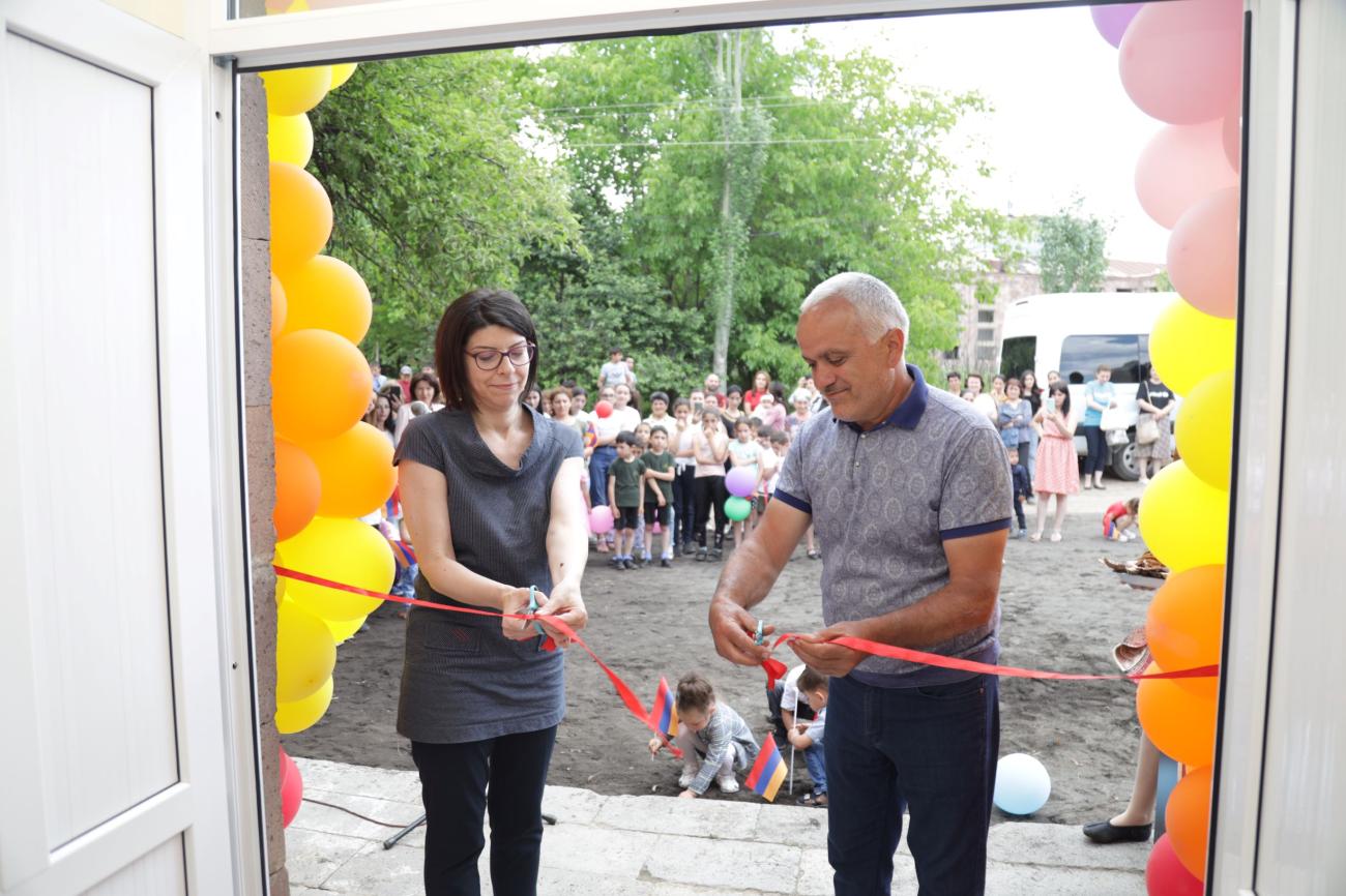 A woman and a man cutting the red ribbon.