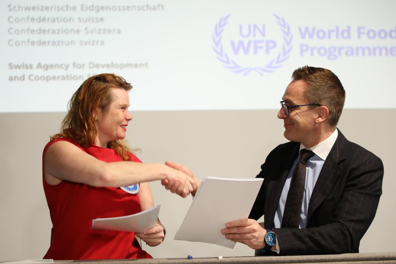 A woman and a man shake hands after signing the agreement.