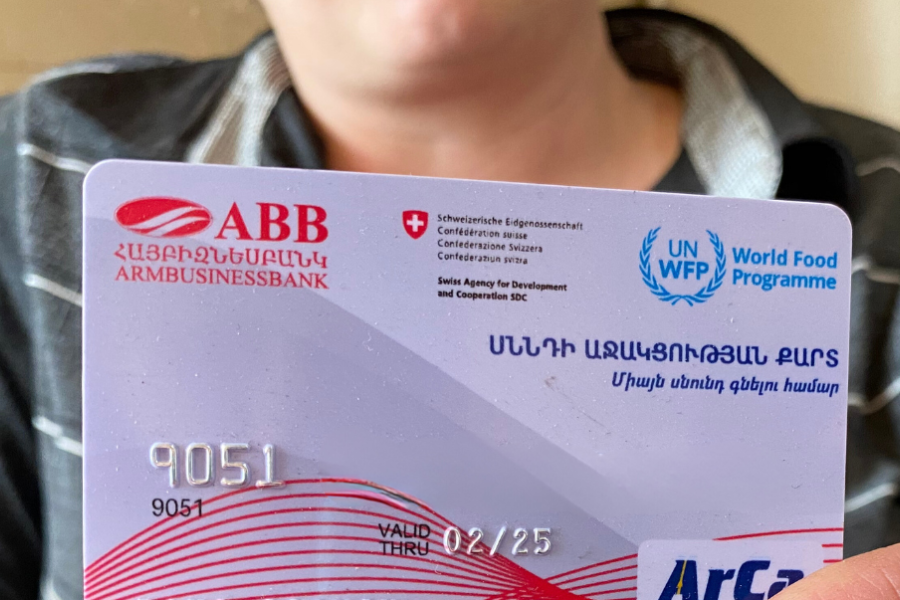 A woman holding a food card provided by WFP Armenia.
