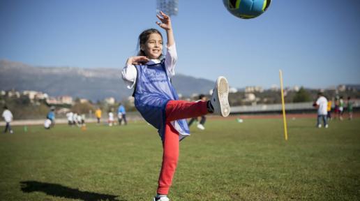 Young girl kicks ball during a refugee solidarity event.