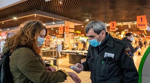 A security guard checks woman's fever with a remote thermometer.