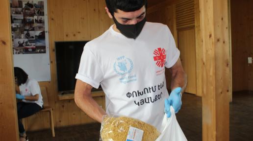 A young man puts WFP branded pasta into a bag.