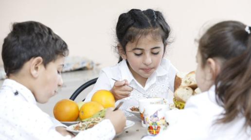 Three school children eating lunch.