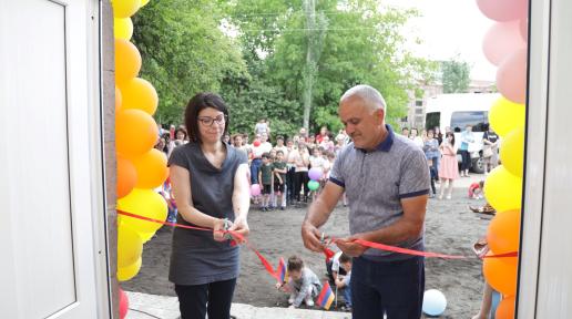 A woman and a man cutting the red ribbon.