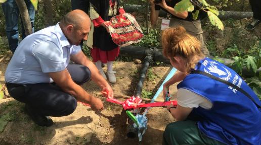A woman and a man cut the red ribbon attached to the water line, marking the beginning of irrigation.